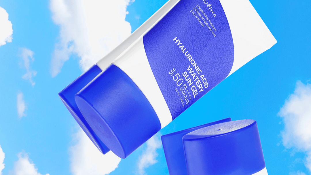 En blå tub av Hyaluronic Acid Watery Sun Gel SPF 50+ mot en himmelsbakgrund med vita moln, illustrerande produktens ljusa och luftiga känsla.