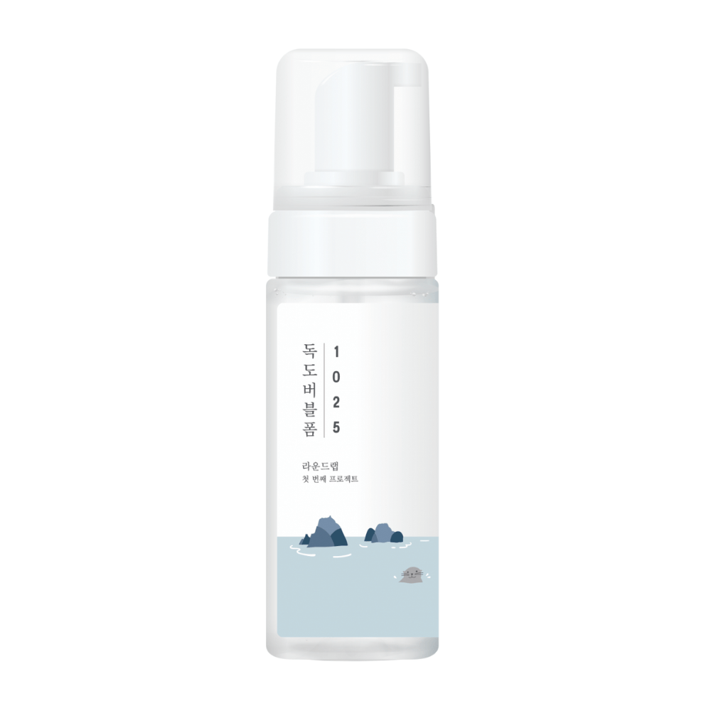 1025 Dokdo Bubble Foam" er et ansigtsrensningsprodukt fra ROUND LAB, pakket i en hvid pumpeflaske med enkelt og rent design, prydet med tekst og minimalistiske illustrationer af havlandskaber. 