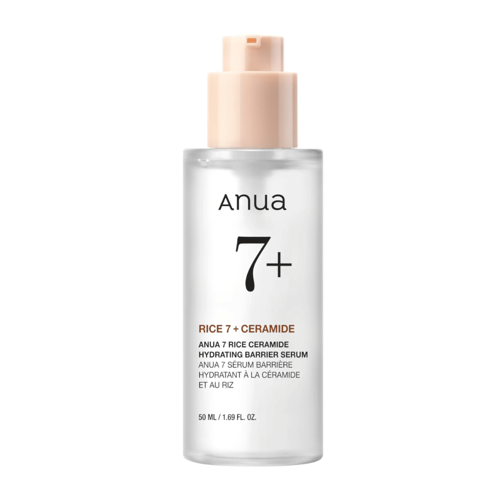 En flaske af "Anua 7+ Rice Ceramide Hydrating Barrier Serum" med et klart og minimalistisk design. Emballagen er transparent med en lyserød pumpe og indeholder 50 ml serum, der er beriget med ris og ceramider for at fugte og styrke hudens barriere.