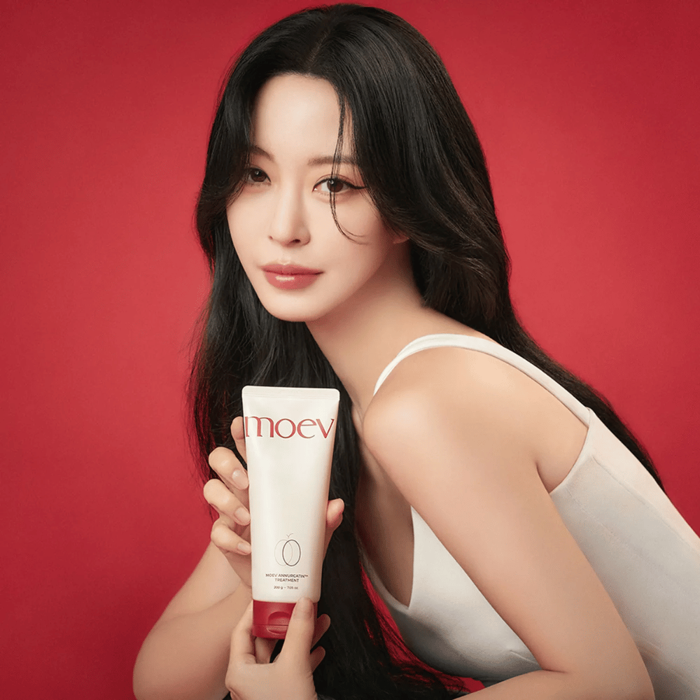 Kvinde med langt, skinnende hår holder MOEV Annurcatin Treatment – koreansk hårpleje, der giver næring, styrke og glans med naturlige ingredienser.