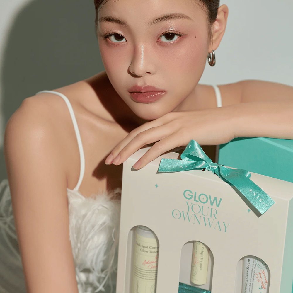 Model med elegant makeup holder i AXIS-Y:s “Glow Your Own Way”-gaveæske – en stilren Hudplejesæt perfekt som gave til dig selv eller en du holder af.