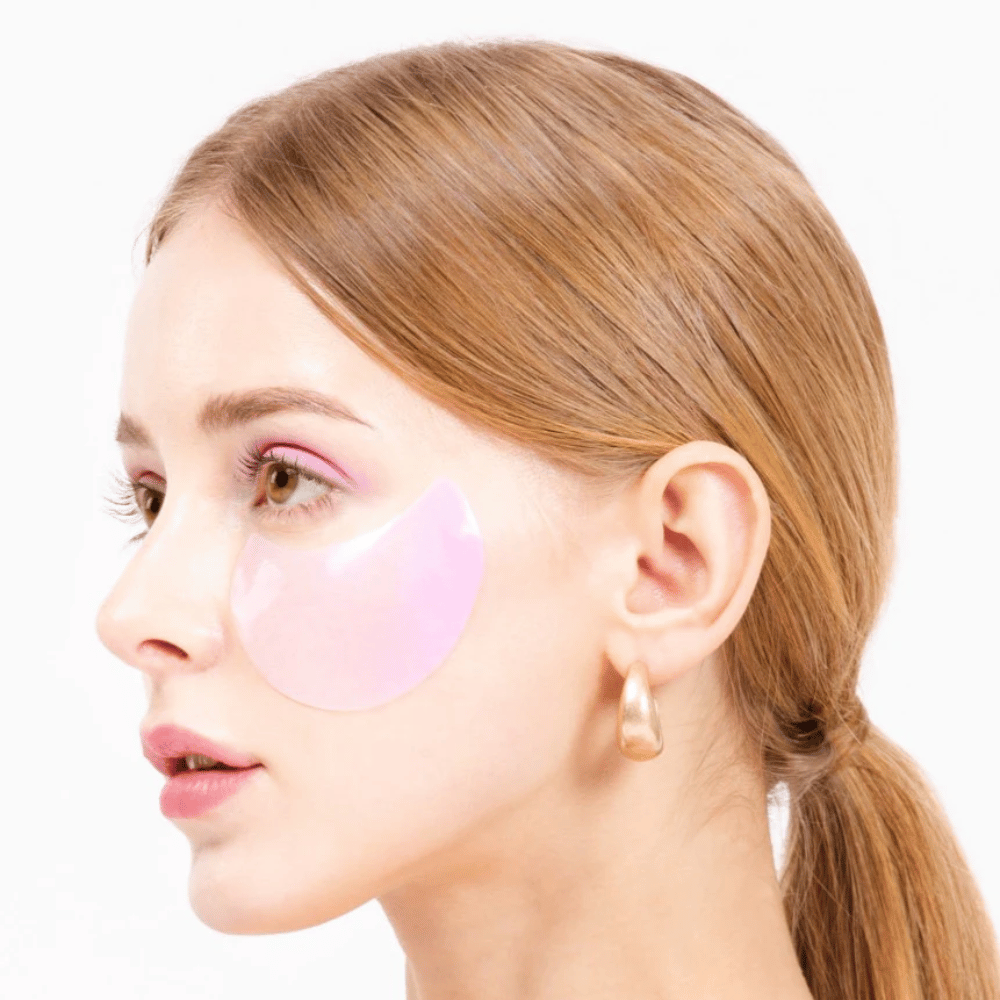 Model bærer et lyserødt hydrogel eye patch under øjet, fugtgivende og hudforyngende.