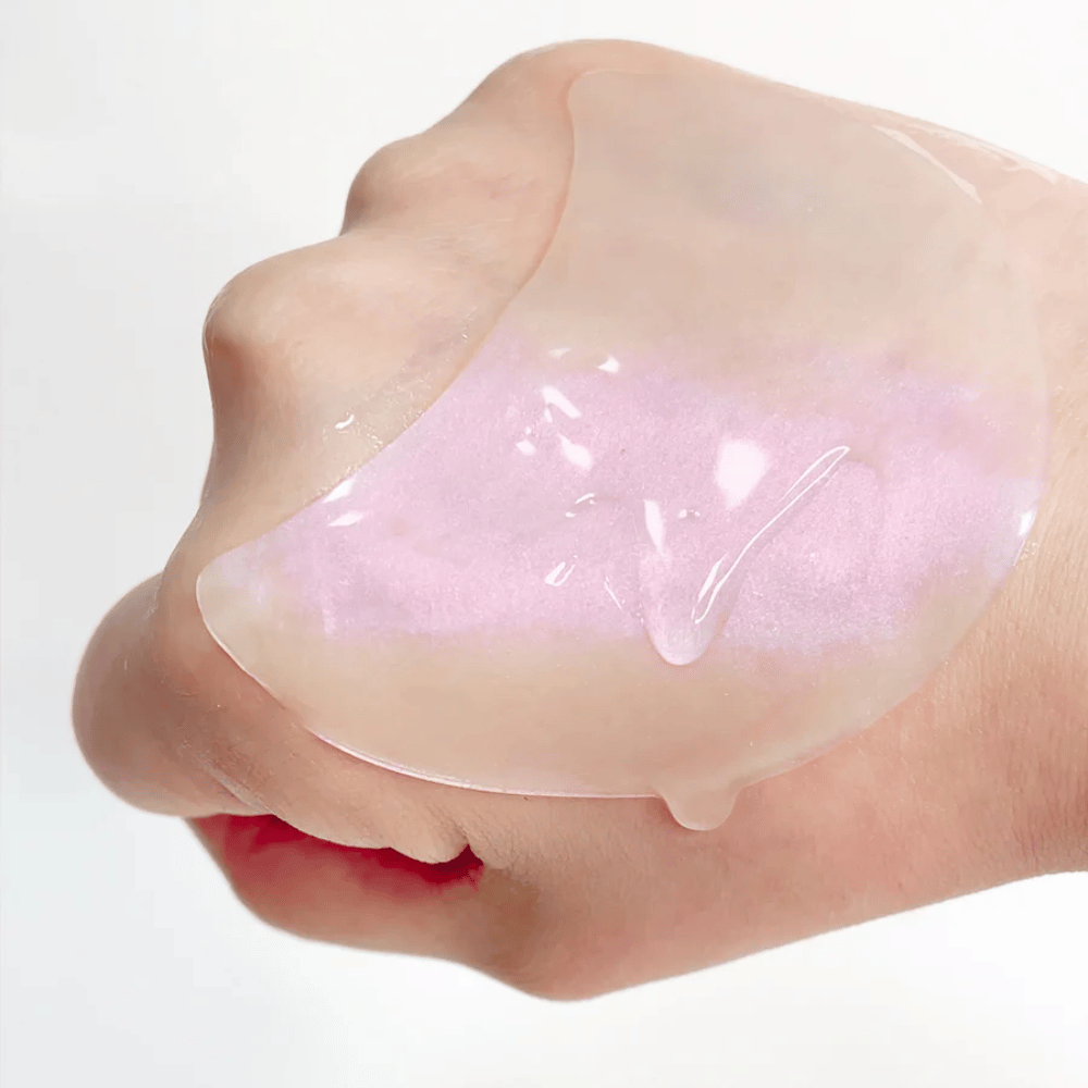 Lyserødt hydrogel eye patch med retinol vises på en hånd, fugtgivende og glansgivende formel.