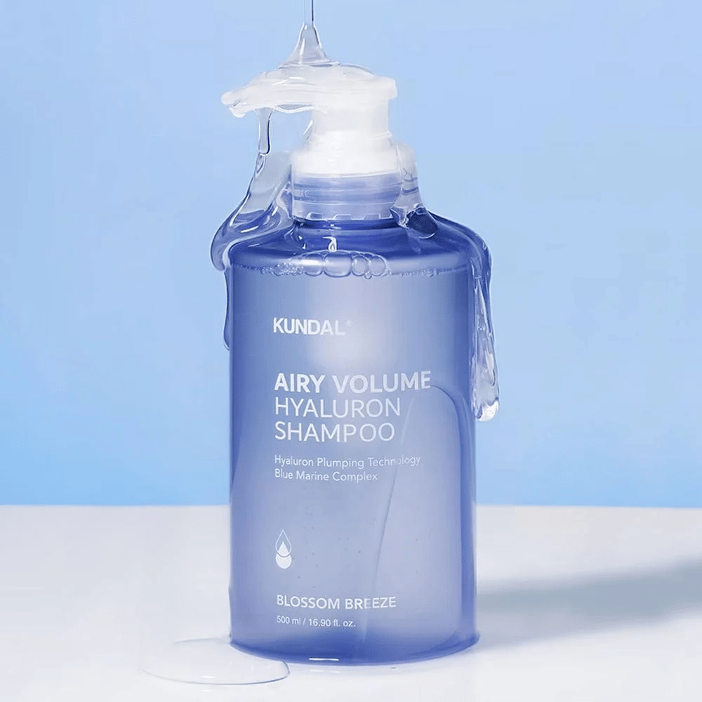 KUNDAL Airy Volume Hyaluron Shampoo Blossom Breeze i blå pumpeflaske, med hyaluron og Blue Marine Complex, fotograferet med rindende vand.