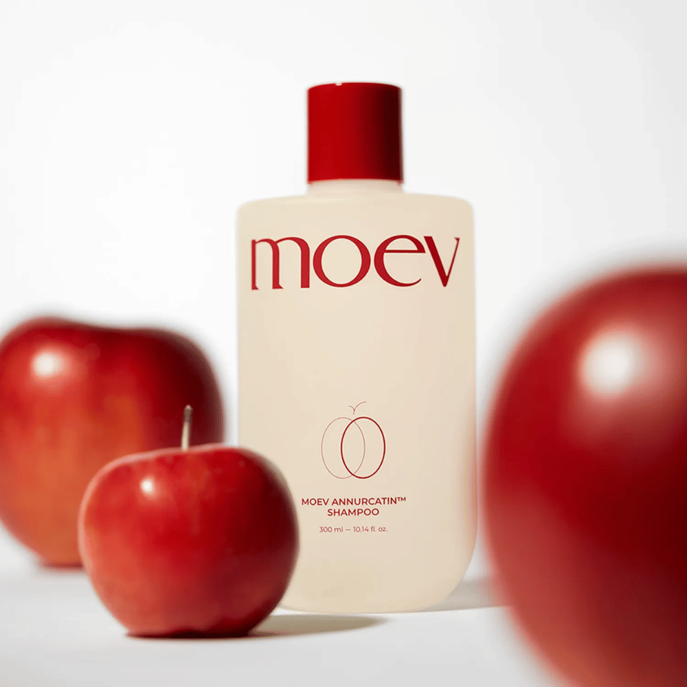 MOEV Annurcatin Shampoo placeret blandt røde æbler – inspireret af Annurca-æblets antioxidanter, der giver stærkere, sundere og mere glansfuldt hår.
