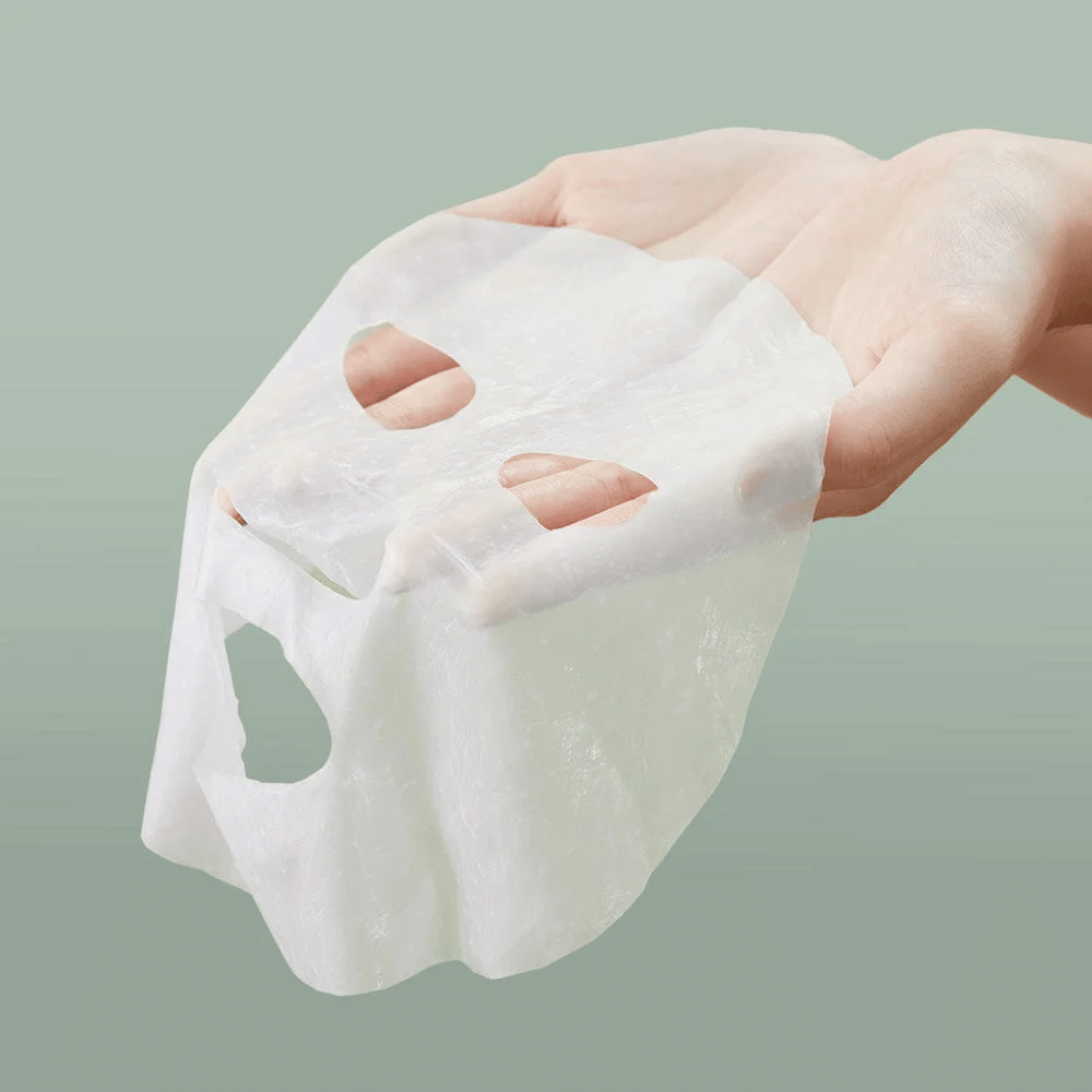 En persons hånd som holder Anua Heartleaf 77% Soothing Sheet Mask.