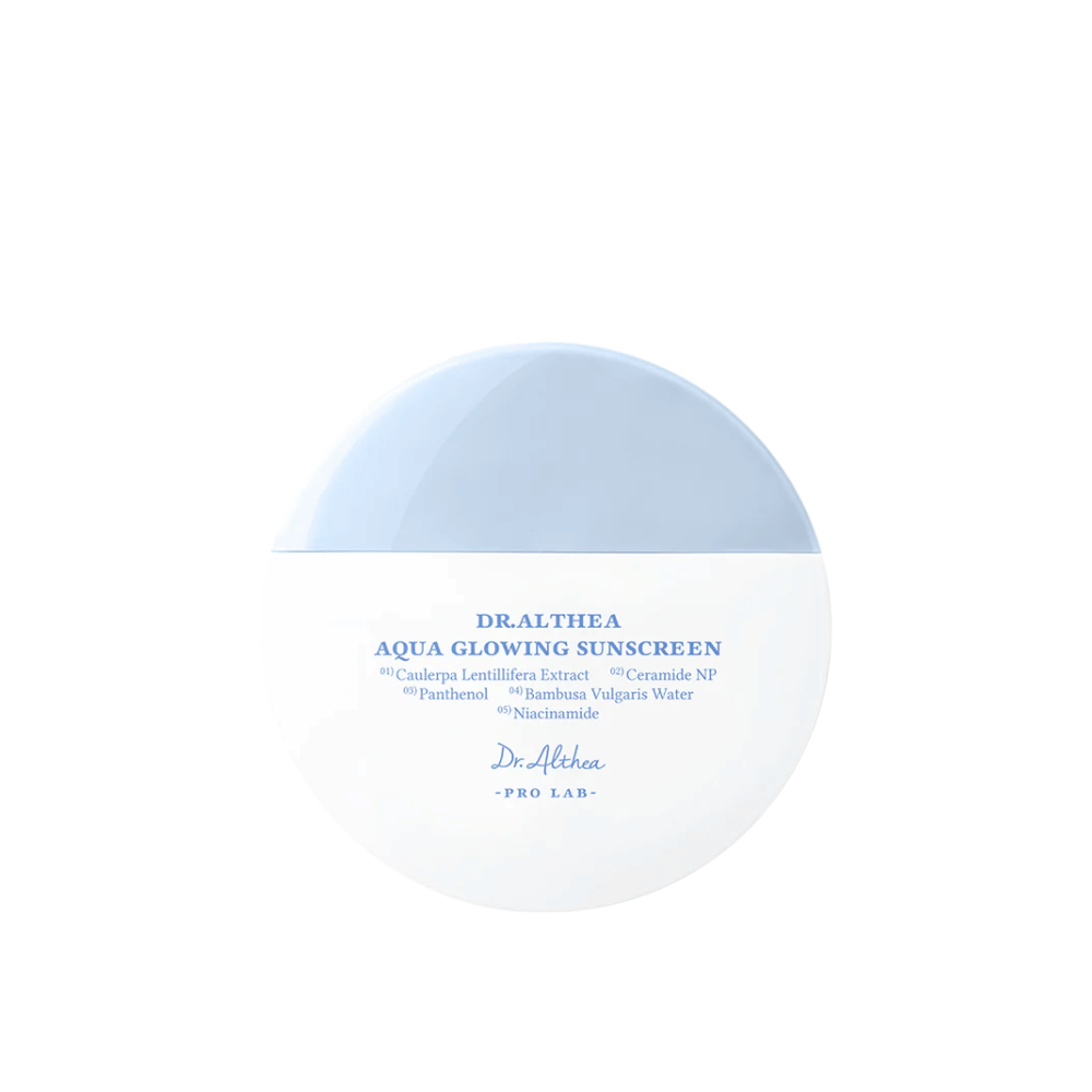Produktbillede af Dr. Althea Aqua Glowing Sunscreen – en rund solcreme i hvid og lyseblå emballage med tekst i blå, der fremhæver fugtgivende ingredienser som niacinamid og ceramider.