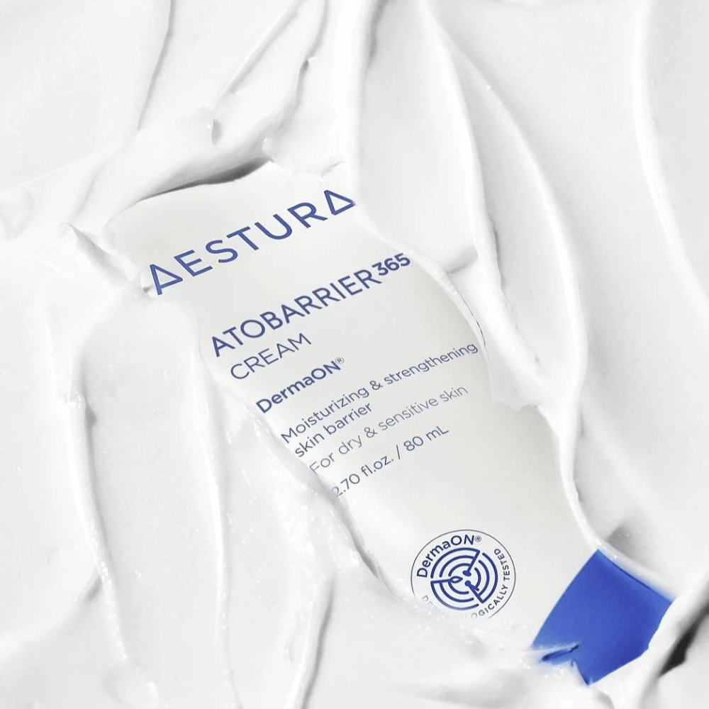 Aestura Atobarrier 365 Cream er perfekt til tør og følsom hud. Med DermaON™ teknologi, fugter og styrker denne creme hudbarrieren. Produktet vises her i en 80 ml tube, delvist dækket af sin egen cremede konsistens, hvilket fremhæver dens rige, fugtgivende egenskaber.