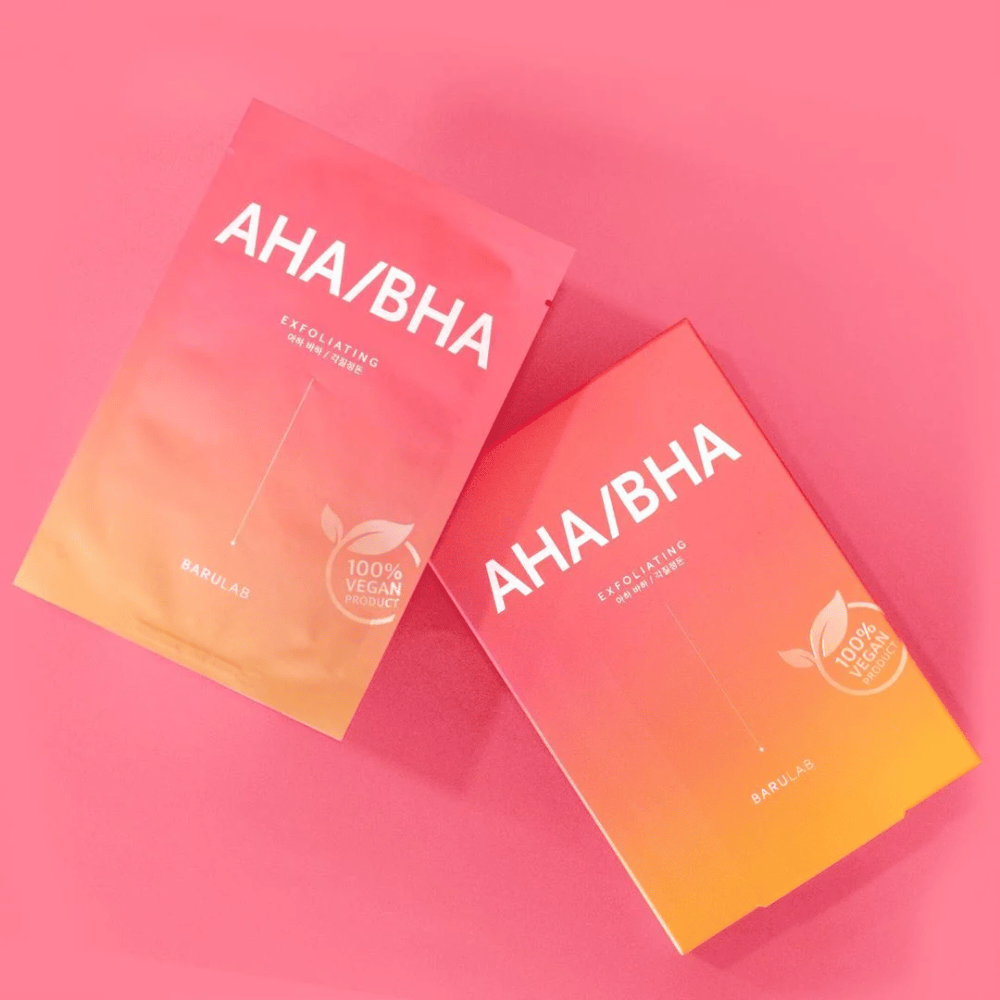 To produkter fra BARULAB, en i en pose og en i en karton, begge mærket med "AHA/BHA" og "Exfoliating" mod en lyserød baggrund. Produkterne er markeret som "100% Vegan Product".