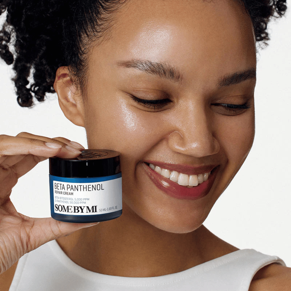 Model med glødende hud holder SOME BY MI Beta Panthenol Repair Cream – koreansk ansigtscreme, der styrker hudbarrieren og fugter.