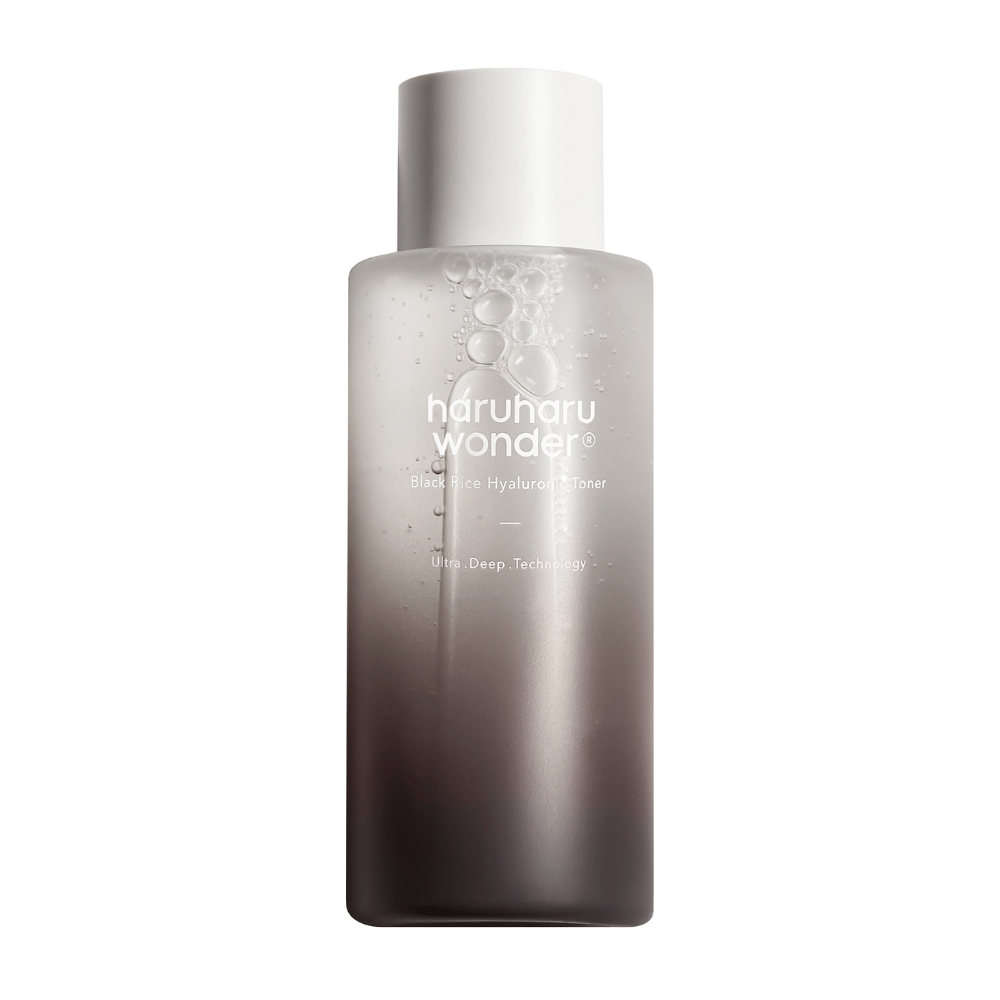 En flaske af haruharu wonder Black Rice Hyaluronic Toner med en grå til hvid farvegradient og vanddråber på overfladen, mod en hvid baggrund.