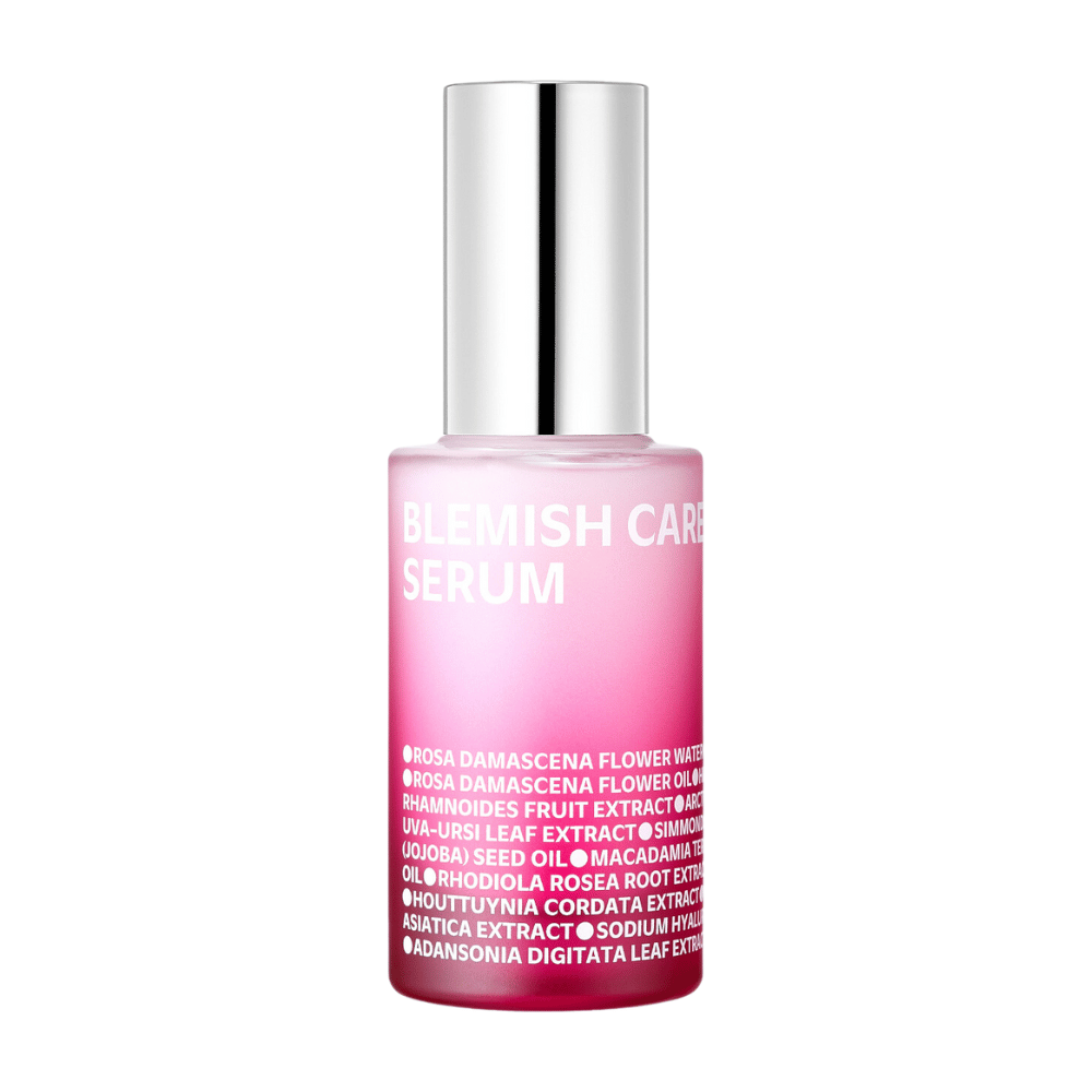 En enkelt flaske Blemish Care Serum med et tonet rosa design og sølvfarvet låg, stående mod en hvid baggrund. Teksten på flasken oplister ingredienser som blandt andet rosenvand, olier og ekstrakter, trykt i hvidt på forsiden.