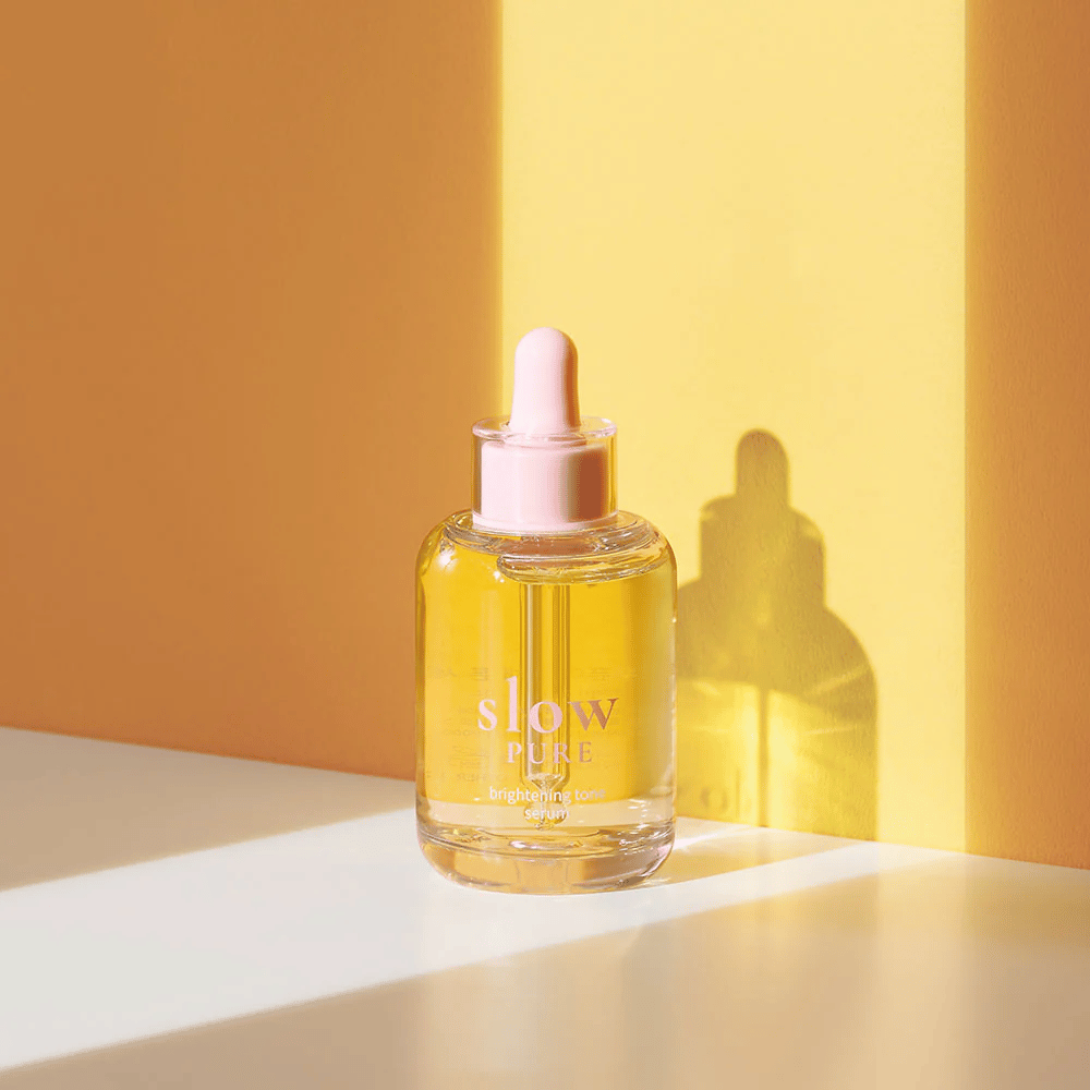 Slow Pure Brightening Tone Serum i solrigt gult lys, symboliserer glans og energi for huden.