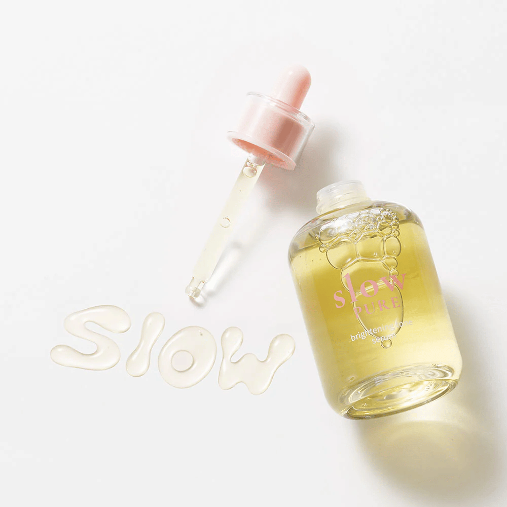 Slow Pure Brightening Tone Serum med åben pipette, tekst skrevet i serum på overfladen: "Slow".