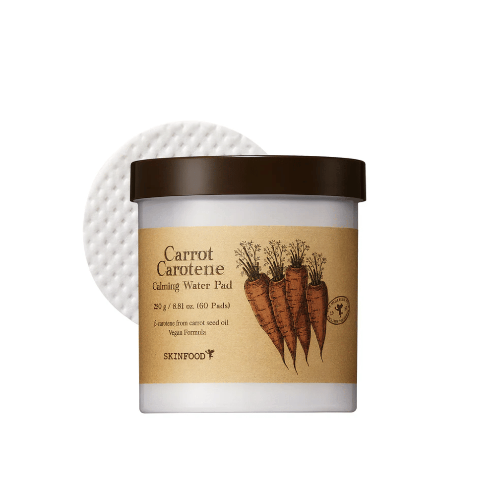En dåse "Carrot Carotene Calming Water Pad" fra SKINFOOD. Dåsen indeholder 60 pads og er mærket med et billede af gulerødder. Produktet, som er baseret på gulerodsfrøolie, er veganervenligt og designet til at berolige huden.