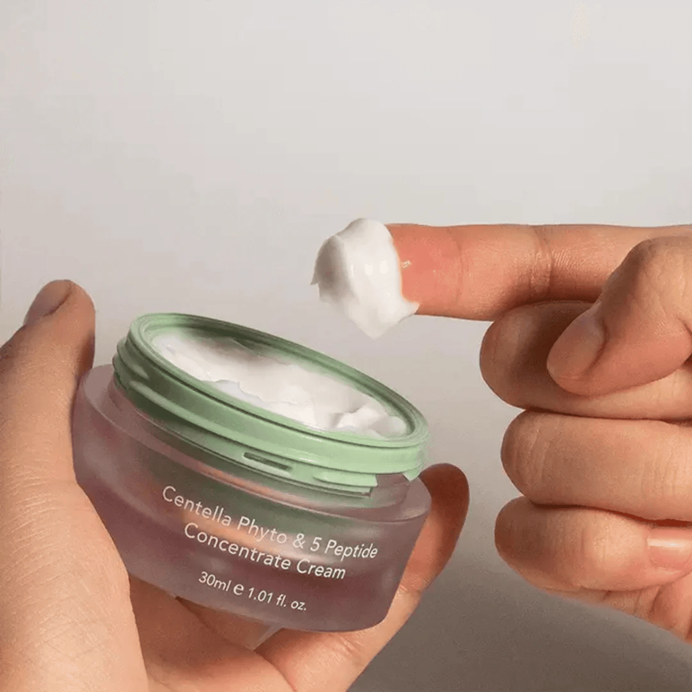 Hånd der tager en klat Centella Phyto & 5 Peptide Concentrate Cream fra en krukke.