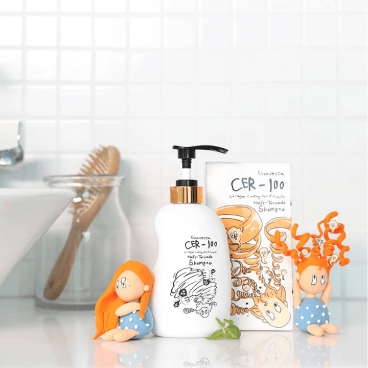 Elizavecca CER-100 Shampoo og æske vises i et badeværelsesmiljø ved siden af en hårbørste og dekorative figurer. Billedet formidler en hverdagsagtig hårplejerutine og produktets anvendelse i hjemmemiljø.