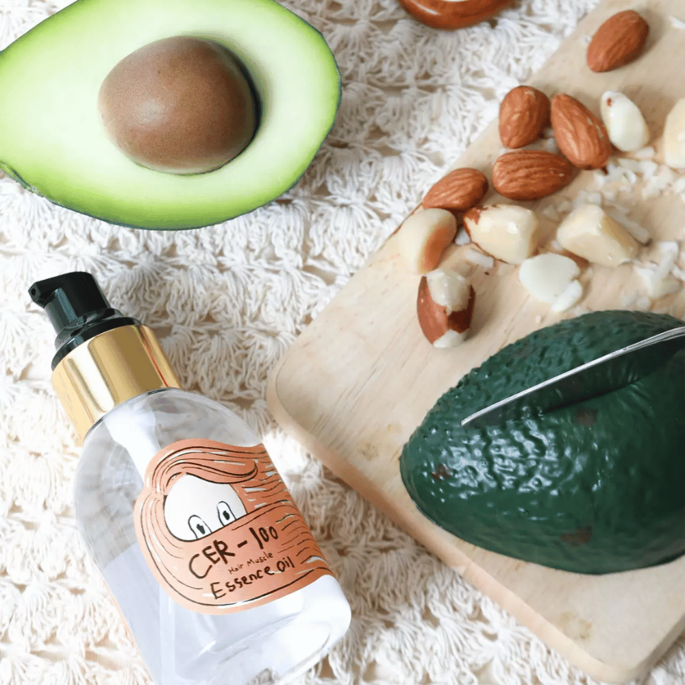 Elizavecca CER-100 Hair Muscle Essence Oil ingredienser – nærbillede med avocado og planteolier, der viser en næringsrig hårolie, som hjælper med at blødgøre og pleje håret.
