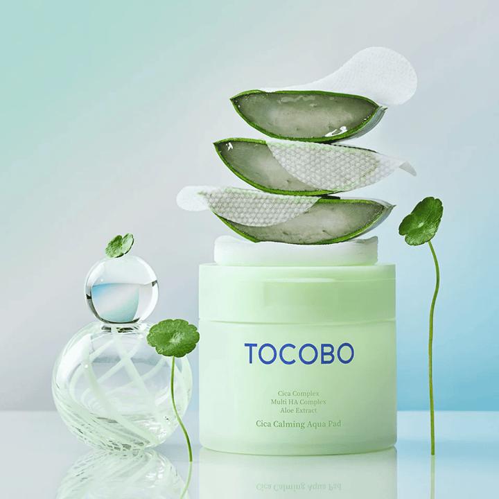 TOCOBO Cica Calming Aqua Pad vises sammen med toner pads, aloe vera og centella asiatica. Billedet fremhæver produktets fugtgivende og beroligende ingredienser.
