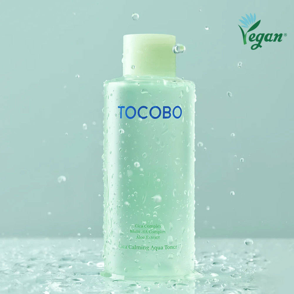 Produktbillede af TOCOBO Cica Calming Aqua Toner omgivet af vanddråber, som fremhæver tonerens fugtgivende og beroligende egenskaber til sensitiv hud.