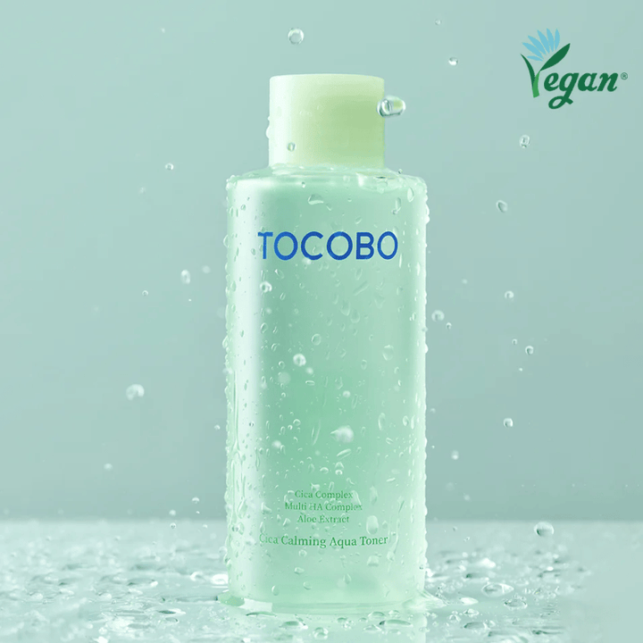 Produktbillede af TOCOBO Cica Calming Aqua Toner omgivet af vanddråber, som fremhæver tonerens fugtgivende og beroligende egenskaber til sensitiv hud.