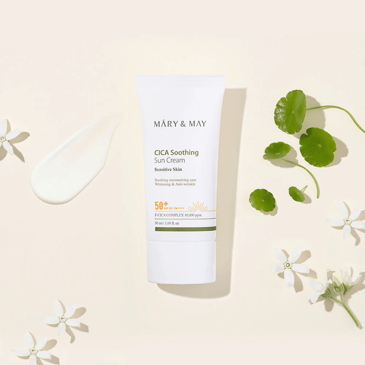Mary&May CICA Soothing Sun Cream SPF50+ PA++++ præsenteret sammen med en cremetekstur, centella-blade og hvide blomster. Billedet fremhæver produktets beroligende egenskaber og fokus på sensitiv hud.