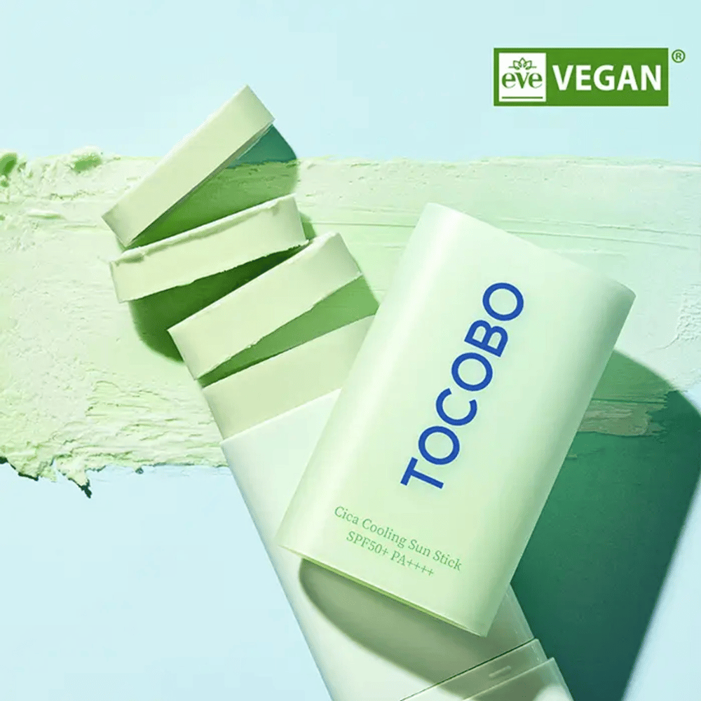 Tocobo Cica Cooling Sun Stick SPF50+ PA++++ i lysegrøn emballage med veganmærkning (EVE VEGAN), liggende på et lag af grønt solstift.