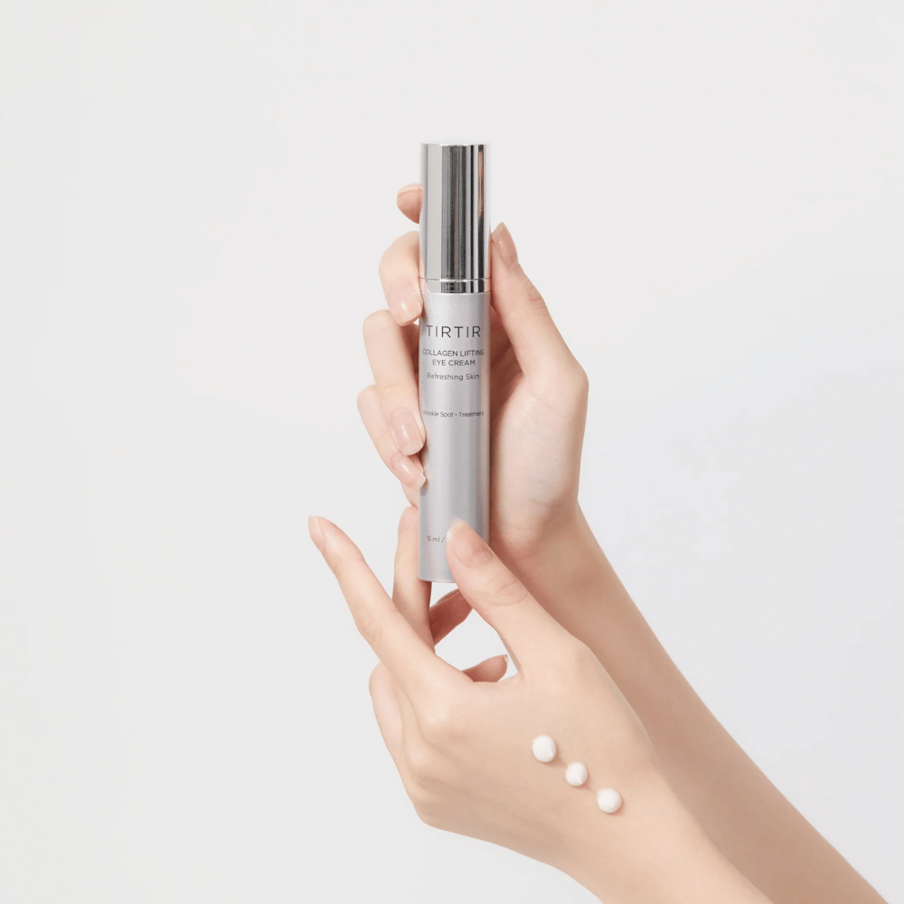 Hænder, der holder en tube med TIRTIR Collagen Lifting Eye Cream, med produkt presset ud på håndryggen.