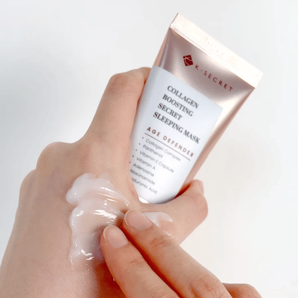 En hånd holder i Collagen Boosting Secret Sleeping Mask mens den anden påfører en generøs mængde creme på oversiden af hånden – viser produktets konsistens og påføring.