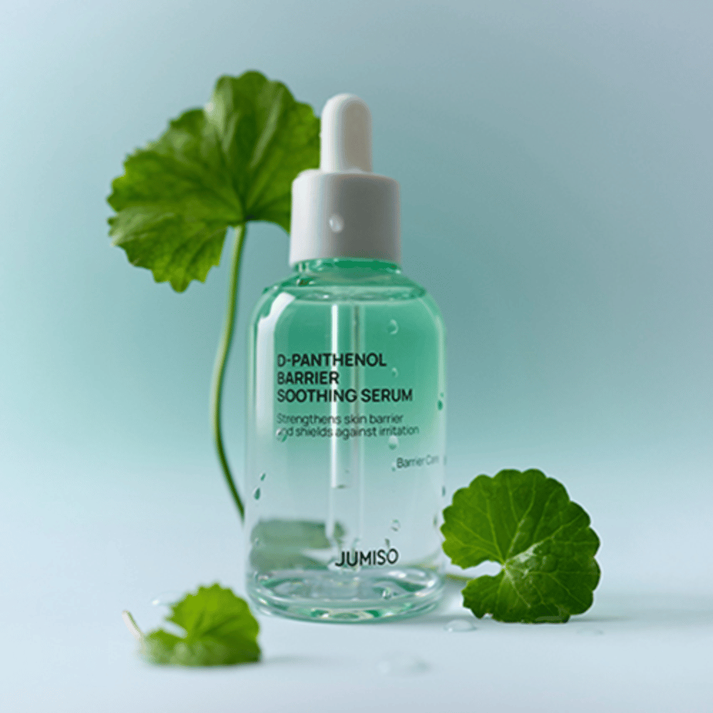 Jumiso D-Panthenol Barrier Soothing Serum i gennemsigtig glasflaske med pipette, placeret med grønne blade i baggrunden.