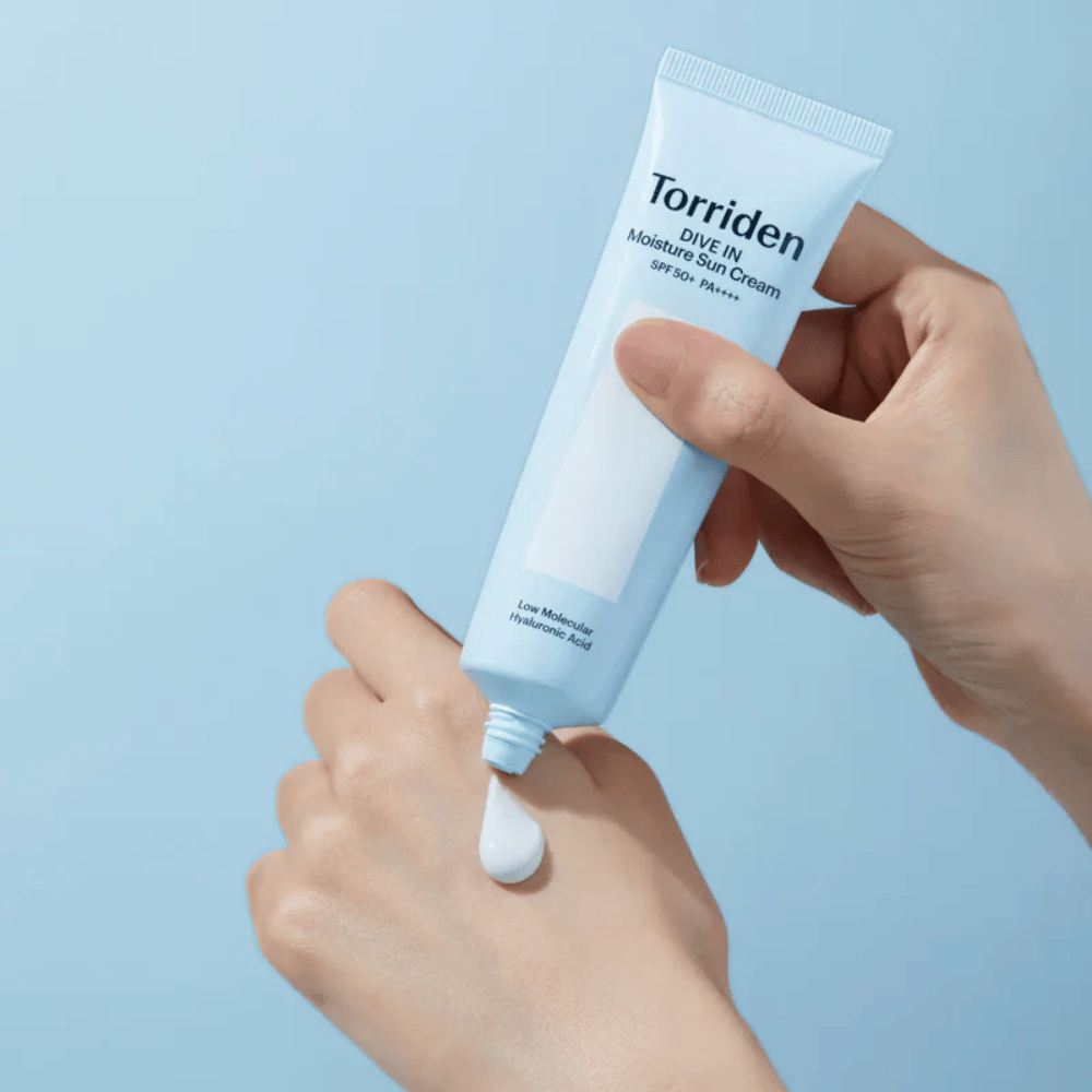 Torriden DIVE-IN Moisture Sun Cream SPF50+ PA++++ påføres på hånden for at vise den fugtgivende solcremes lette og cremede konsistens.
