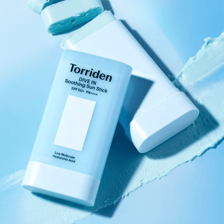 Torriden DIVE IN Soothing Sun Stick SPF50+ PA++++ sammen med udsmurt produkttekstur, som illustrerer den fugtgivende og lette påføring.