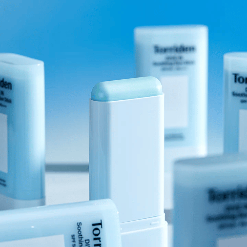 Nærbillede af Torriden DIVE IN Soothing Sun Stick, som viser den bløde solbeskyttelsesformel i stickformat med flere produkter i baggrunden.