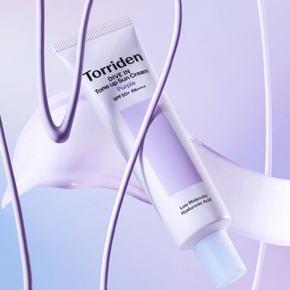 Torriden DIVE IN Tone Up Sun Cream Purple SPF50+ PA++++ præsenteret i et kreativt produktmiljø med lilla detaljer, der fremhæver den fugtgivende formel.