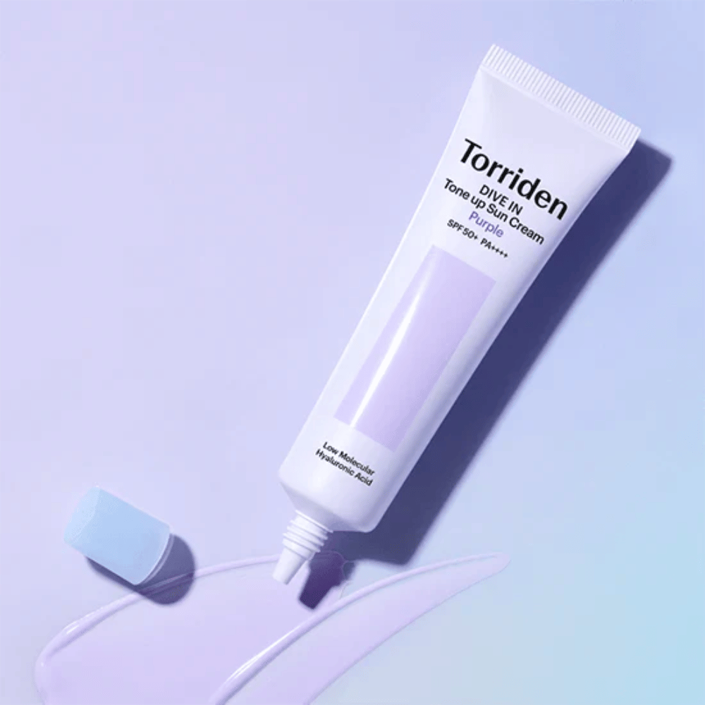 Åben tube af Torriden DIVE IN Tone Up Sun Cream Purple med lilla tonet solcremetekstur, som viser produktets farvekorrigerende formel.