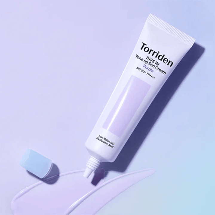 Åben tube af Torriden DIVE IN Tone Up Sun Cream Purple med lilla tonet solcremetekstur, som viser produktets farvekorrigerende formel.