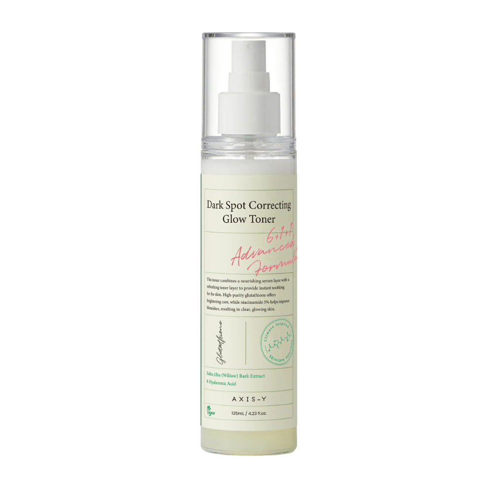 Et billede af en flaske af produktet "AXIS-Y Dark Spot Correcting Glow Toner". Flasken er gennemsigtig med en hvid etiket og tekst i sort og grønt. Produktet er en toner i sprayform, og flasken indeholder 125 ml (4,23 fl. oz). Etiketten nævner nøgleingredienser som Willow Bark Extract og Hyaluronic Acid.