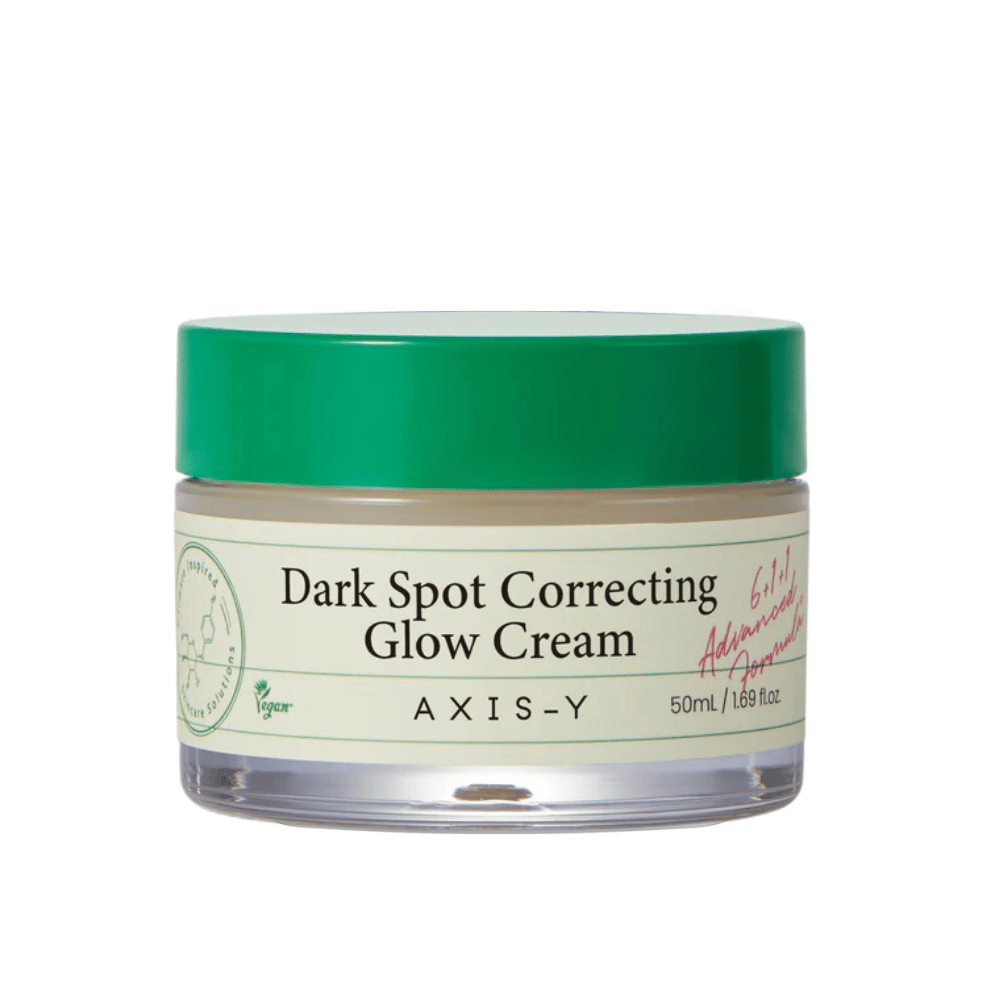 En krukke af "AXIS-Y Dark Spot Correcting Glow Cream". Denne creme er beregnet til at korrigere mørke pletter og give huden glød. Emballagen er elegant med en gennemsigtig bund og et iøjnefaldende grønt låg.