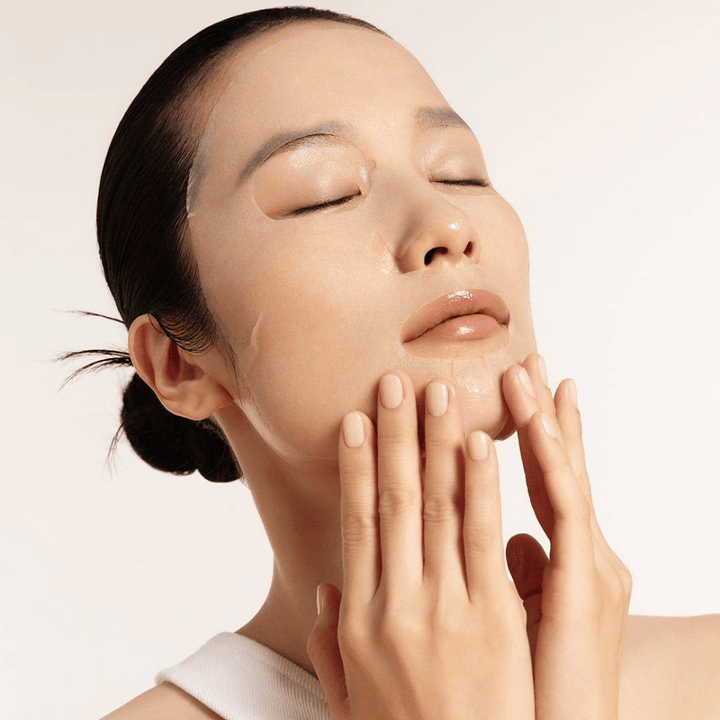 Model med fugtet og strålende hud anvender Sheet mask, fokus på glød, jævn hudtone og glow.