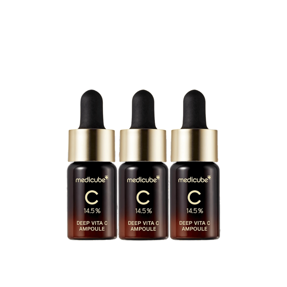Tre flasker af Medicube Deep Vita C Ampoule, med 14,5 % C-vitamin, arrangeret på række. Flaskerne har et elegant design med mørkebrun bund og guldfarvet kork. Perfekt til lysere hudtone og jævnere hudtekstur.