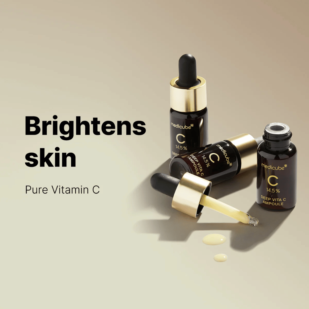 Medicube Deep Vita C Ampoule med 14,5 % C-vitamin, vises i elegante flasker med guldfarvede pipetter. Produktet er designet til at lysne hudtonen og give en strålende hud. Teksten "Brightens skin" og "Pure Vitamin C" forstærker budskabet.