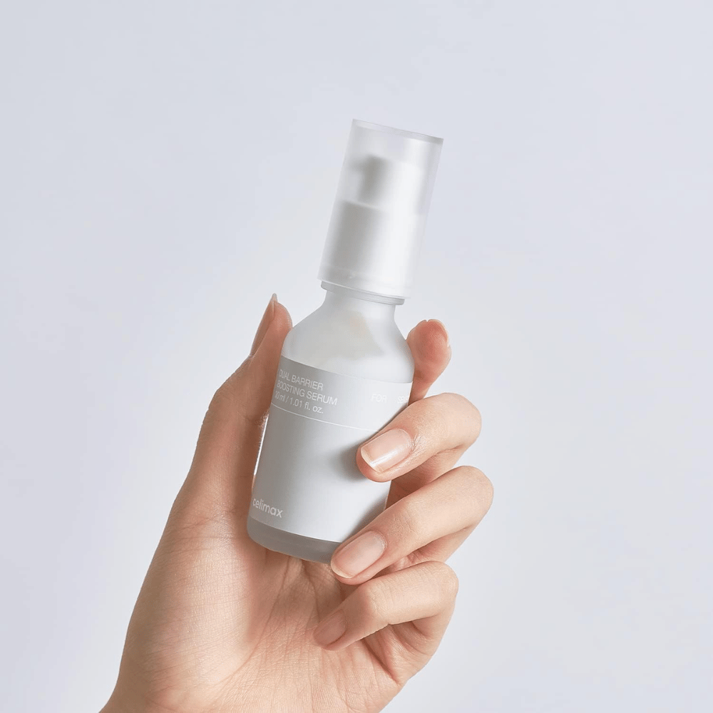 Celimax Dual Barrier Boosting Serum i hånd, minimalistisk emballage der viser barriereforstærkende koreansk serum til sensitiv hud.