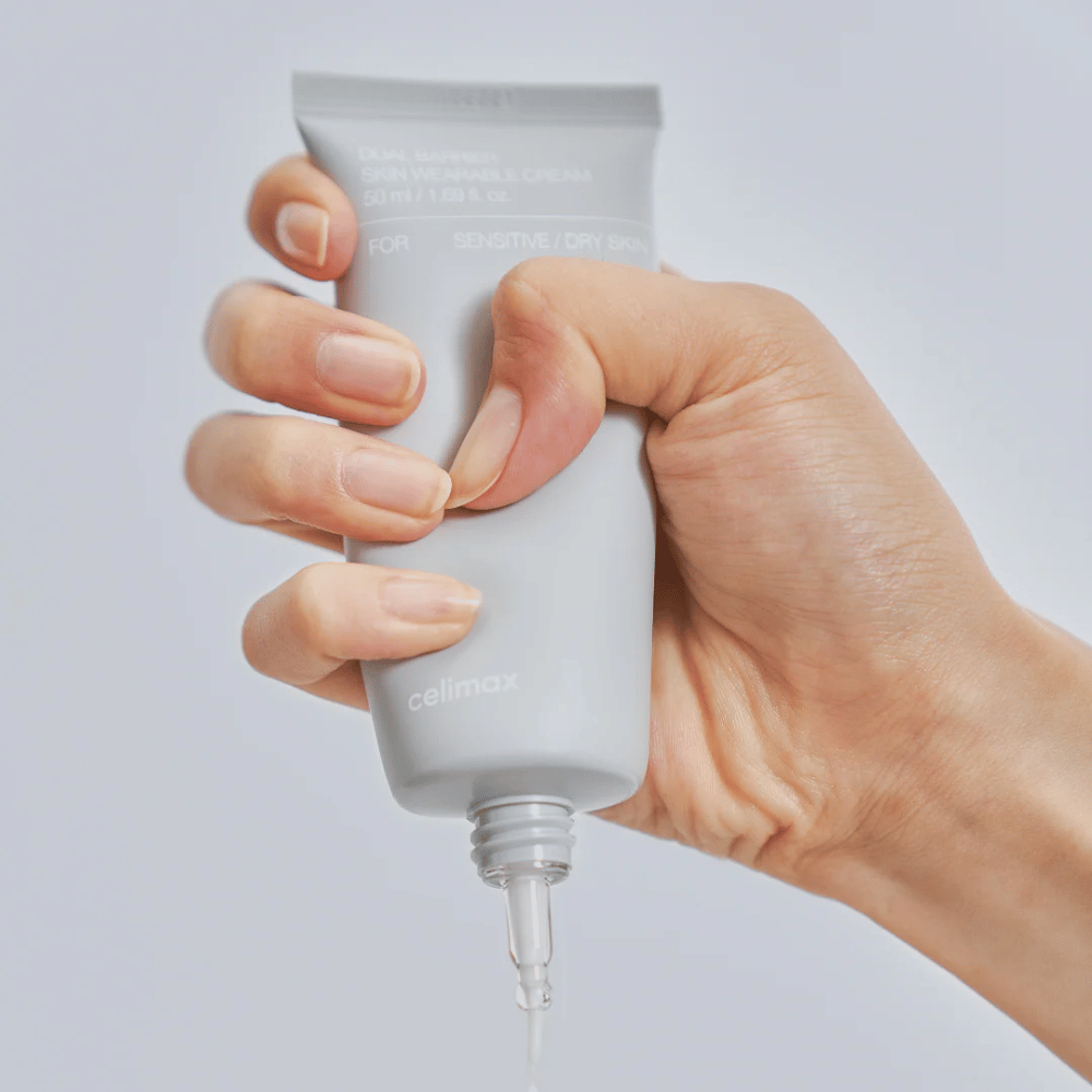 Hånd der påfører Celimax Dual Barrier Skin Wearable Cream, barriereforstærkende ansigtscreme til følsom og tør hud, der giver langvarig fugt og beskytter hudbarrieren.