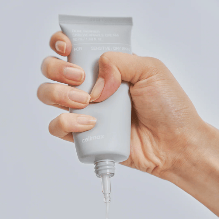 Hånd der påfører Celimax Dual Barrier Skin Wearable Cream, barriereforstærkende ansigtscreme til følsom og tør hud, der giver langvarig fugt og beskytter hudbarrieren.
