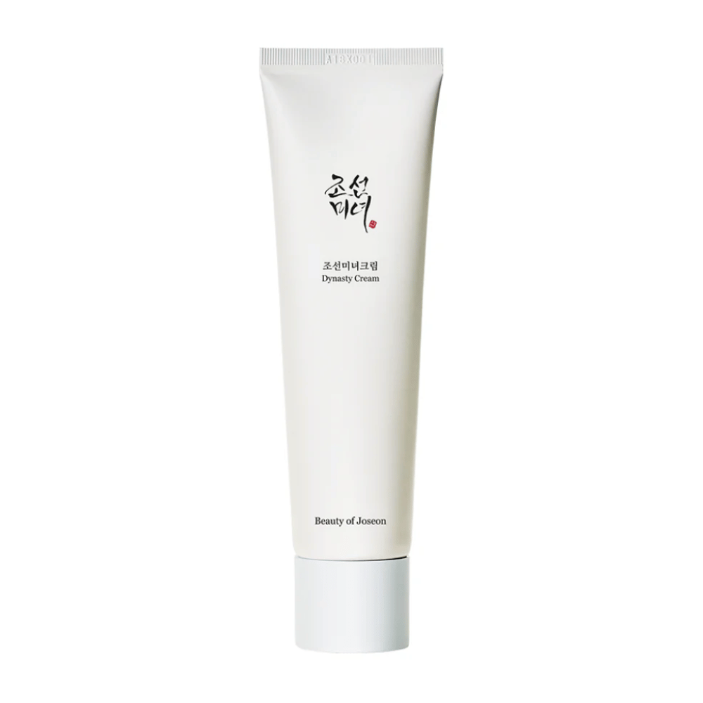 Billedet viser en tube af "Beauty of Joseon Dynasty Cream". Den slanke, hvide tube har minimalistiske designelementer, inklusive elegant sort og rød tekst. Dette hudplejeprodukt lover at nære og vitalisere huden, hvilket afspejler de historiske skønhedshemmeligheder fra Joseon-dynastiet.