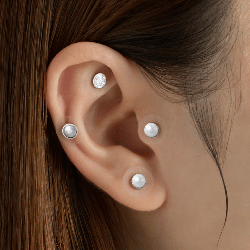Nærbillede af et øre med flere RETURNITY Ear Therapy Acupressure Patch påført på forskellige områder af øret til akupressur og et stilrent look.