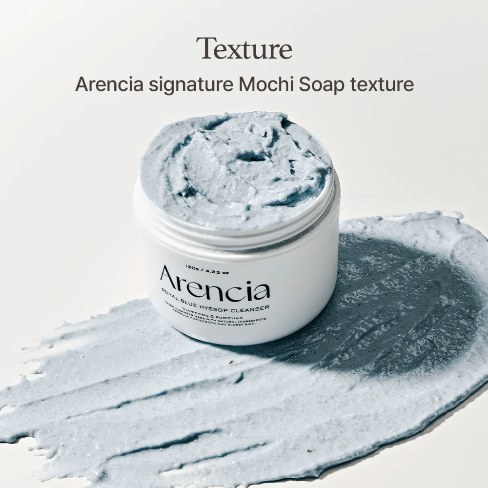 Åben krukke med Arencia Fresh Blue Hyssop Rice Mochi Cleanser, placeret ovenpå et udsmurt lag af den blå, cremede rengøringsformel, der viser dens mochi-lignende tekstur.
