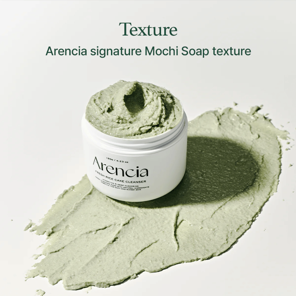 Arencia Fresh Rice Cake Cleanser i åben krukke med cremet grøn mochi-lignende struktur spredt rundt om krukken på en hvid overflade.