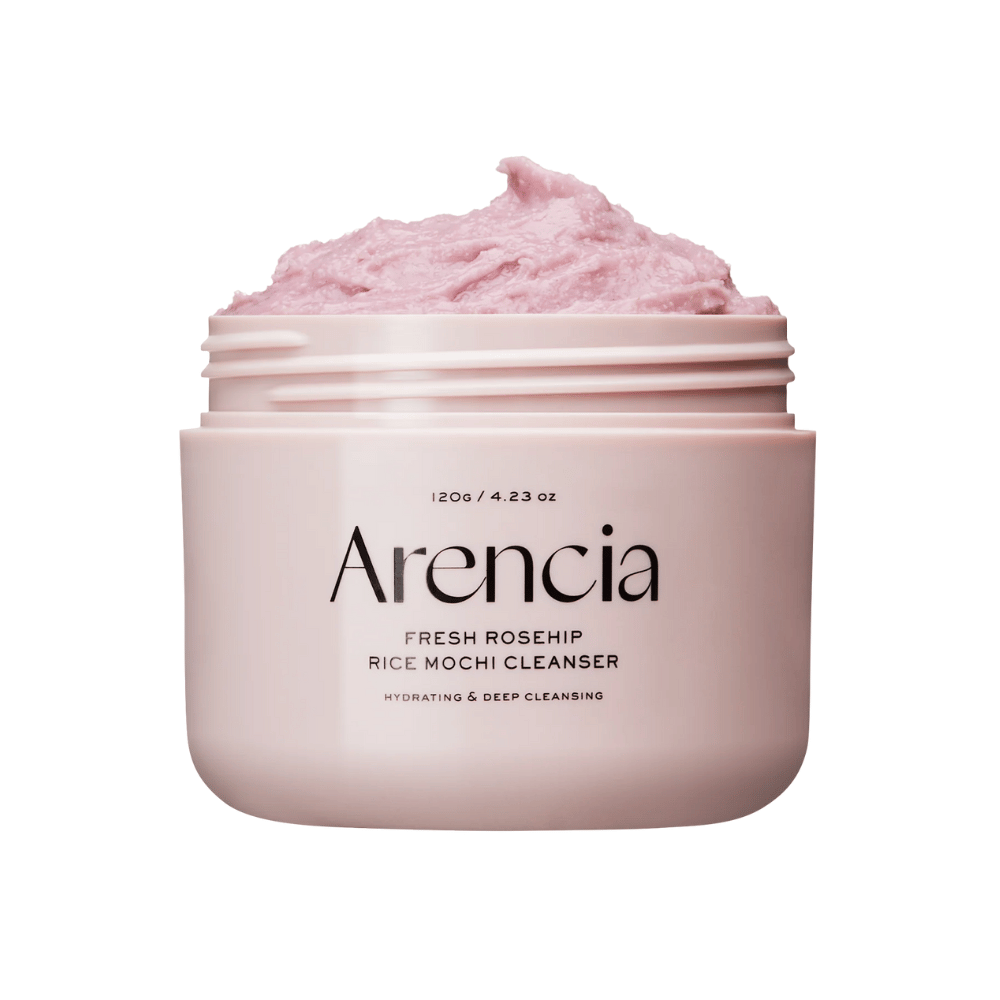 Nærbillede af en lyserød krukke med Arencia Royal Rosehip Cleanser, fyldt med lyserød rensecreme med pisket, mochi-lignende tekstur. Teksten på krukken viser, at produktet fugter og renser i dybden.