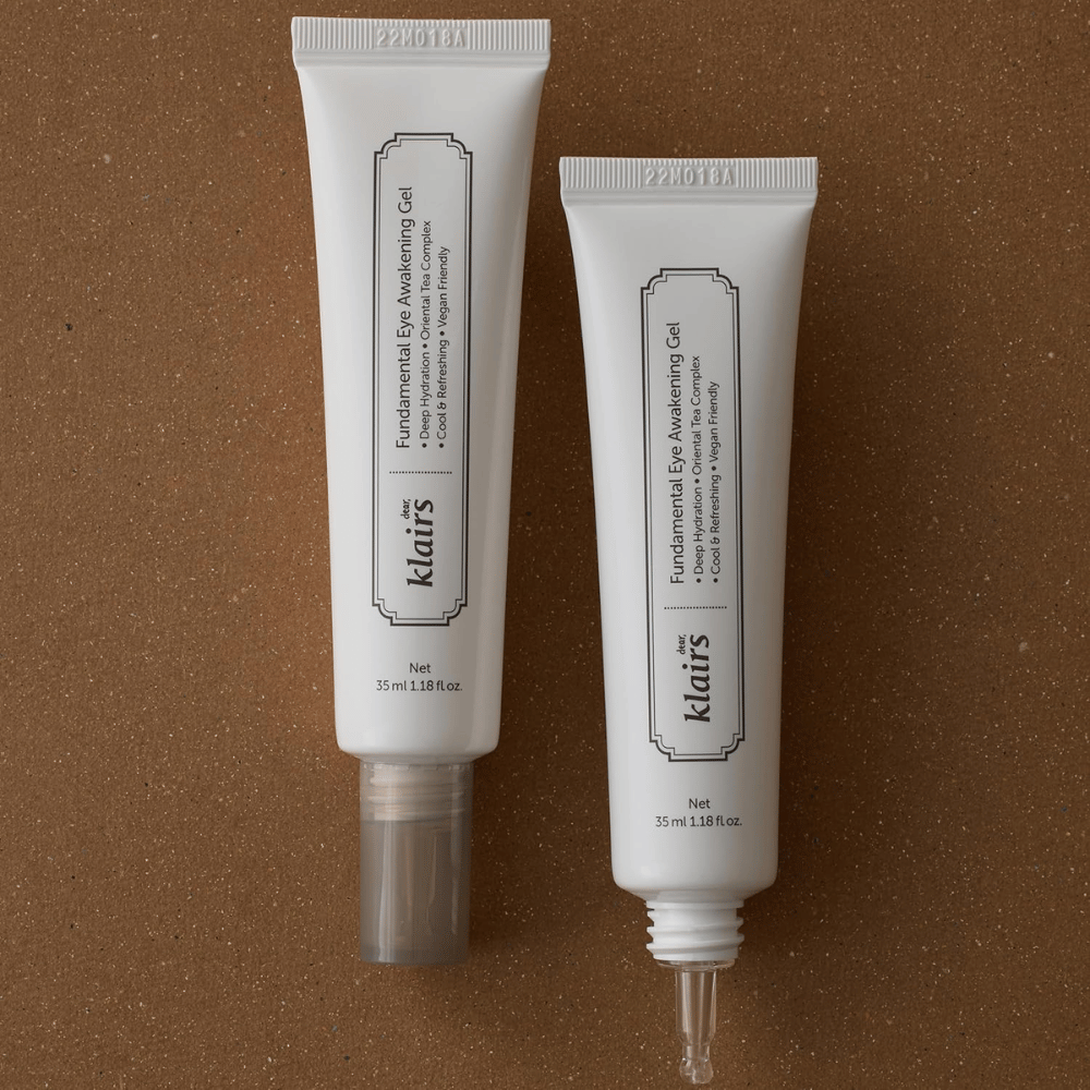 Produktbillede, der viser Klairs Fundamental Eye Awakening Gel i to udgaver – en lukket tube og en åben tube, der fremhæver den smalle applikatorspids. Emballagen har et minimalistisk hvidt design og fremhæver produktets fokus på fugt, kølende følelse og opfriskende pleje af øjenområdet.